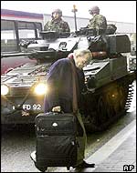 A passenger passes in front of UK troops at Heathrow airport