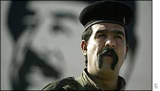 Iraqi soldier in front of a Saddam Hussein poster