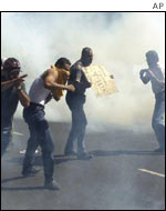 Opposition protesters run through tear gas