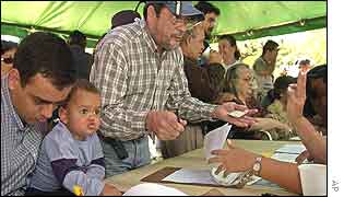 Cristobal Abreu, left, signs a petition as his son Jesus, 2, looks on in Caracas, Venezuela 